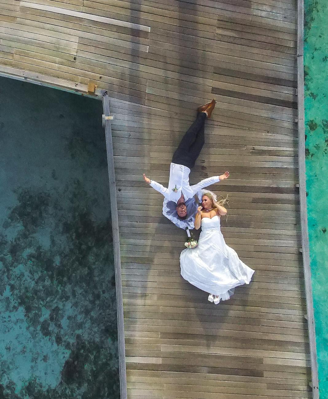 photo of bride and groom laying on pier